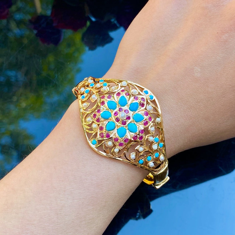 an indian jewellers turquoise bracelet made in gold and studded with stones